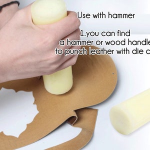 May include: A hand holding a white foam mallet over a piece of brown leather with a die cut design. The text "Use with hammer 1.you can find a hammer or wood handle to punch leather with die cut" is visible in the image.
