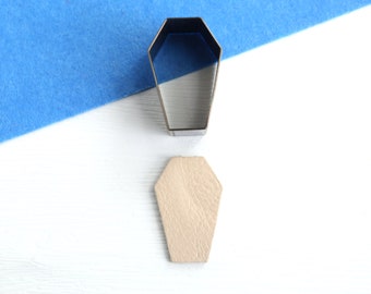 May include: A metal coffin-shaped cookie cutter and a wooden cutout of a coffin.