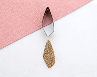 May include: A gold leather piece cut out in the shape of a teardrop using a metal teardrop-shaped cutter.