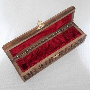 May include: A wooden box with a red velvet interior. The box has a carved design and a brass latch.