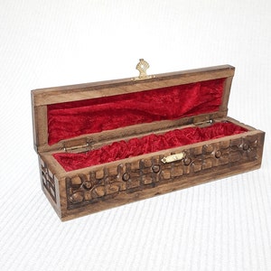 May include: A wooden box with a carved design and a red velvet interior. The box has a brass latch and hinges.
