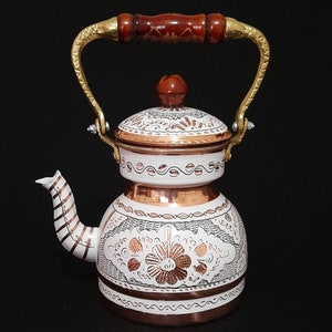 May include: White and copper Turkish tea kettle with a floral design and a wooden handle.