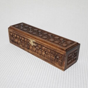 May include: A wooden box with a carved design and a brass latch. The box is brown and has a rectangular shape.