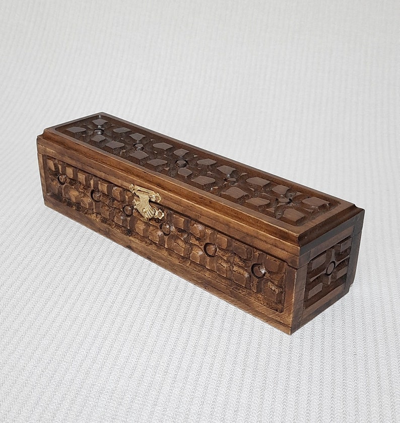 May include: A wooden box with a carved design and a brass latch. The box is brown and has a rectangular shape.