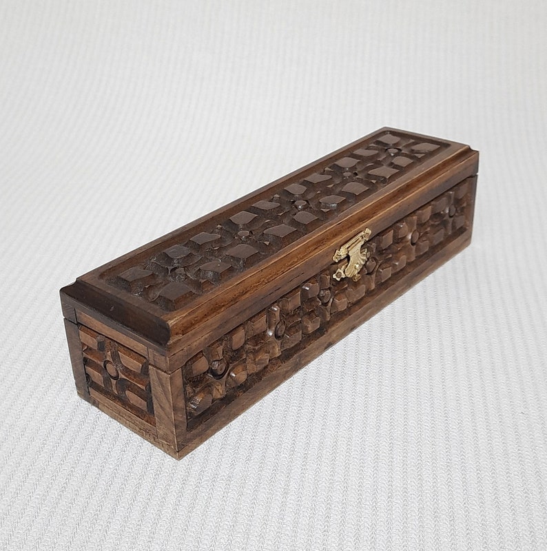 May include: A dark brown wooden box with intricate carvings and a brass latch. The box has a rectangular shape and is made of solid wood.