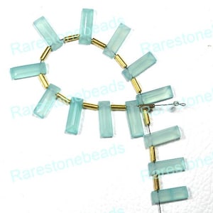 May include: A strand of light blue gemstone beads separated by gold spacers. The beads are rectangular and have a frosted finish. The strand is strung on a wire and has a small loop at the end.