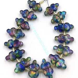 Peut inclure: Un brin de perles de verre irisées en forme de papillons. Les perles sont d'un mélange de couleurs bleu, vert, violet et or.
