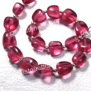 Puede incluir: Una hebra de cuentas de piedras preciosas rosadas con forma cuadrada. Las cuentas están enhebradas en alambre plateado.