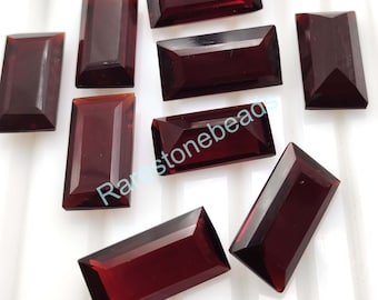 May include: Eight rectangular red gemstones with a faceted cut. The gemstones are scattered on a white surface.