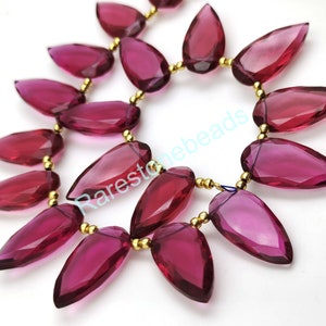 Può includere: Una collana di perle di quarzo rosa sfaccettate a forma di goccia con distanziatori dorati. Le perle sono infilate su un filo dorato.