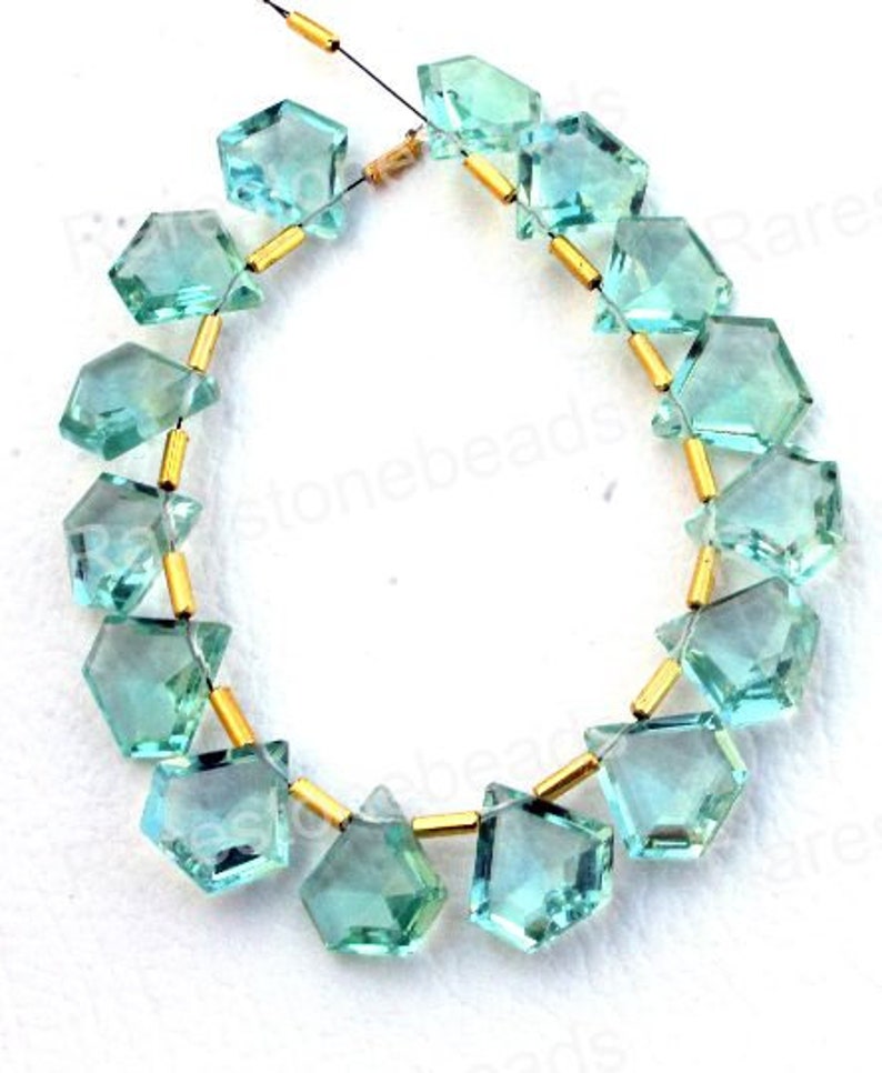 Puede incluir: Una hebra de cuentas de piedras preciosas facetadas de color azul claro con separadores dorados. Las cuentas tienen forma de diamante con esquinas redondeadas. La hebra est&aacute; enhebrada en un hilo transparente.