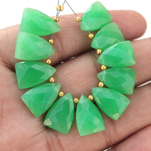 Può includere: Una collana di perle di pietre preziose verdi, ogni perla è sfaccettata e a forma di triangolo. Le perle sono infilate su un filo con distanziatori dorati tra ogni perla.