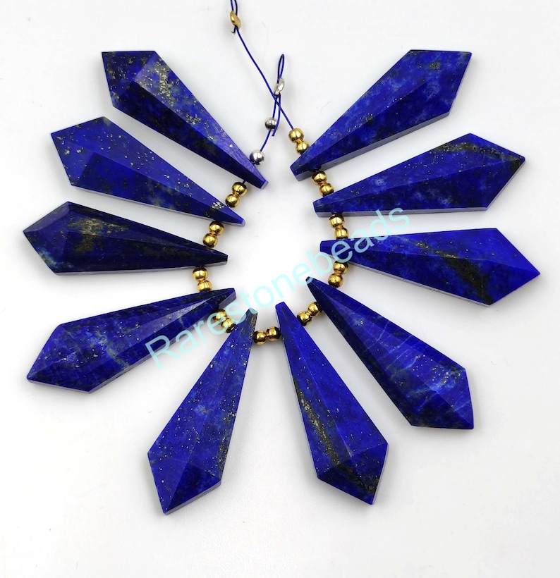 May include: Ten dark blue lapis lazuli gemstone beads with gold accents. The beads are faceted and shaped like teardrops. The beads are strung on a gold chain.