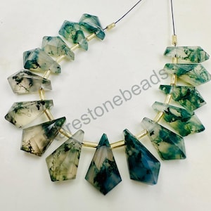 Puede incluir: Una hebra de cuentas de piedra de ágata verde y blanca, cada cuenta está facetada y tiene forma de lágrima. Las cuentas están enhebradas en un alambre delgado con separadores de color dorado entre cada cuenta.