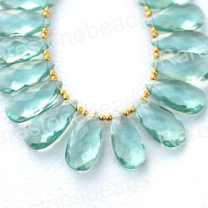 Peut inclure: Un collier de perles de pierres précieuses bleu clair avec des accents dorés. Les perles sont facettées et ont une forme de larme. Les perles sont enfilées sur un fil transparent.