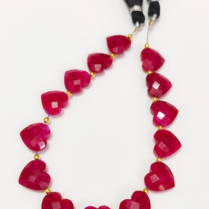 Puede incluir: Una hebra de cuentas de rubí en forma de corazón con separadores dorados. Las cuentas son facetadas y tienen un color rojo intenso.