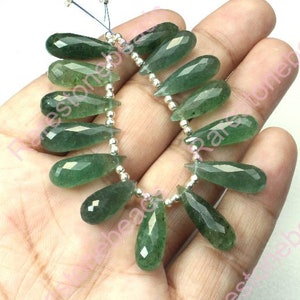 Puede incluir: Una hebra de cuentas de piedras preciosas verdes, cada cuenta tiene forma de lágrima con bordes facetados. Las cuentas están enhebradas en un alambre de plata con cuentas espaciadoras de plata.