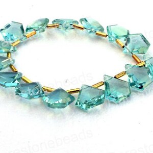 Puede incluir: Una hebra de cuentas de piedras preciosas de color azul claro facetadas con separadores dorados. Las cuentas tienen forma de diamantes y est&aacute;n enhebradas en un alambre.
