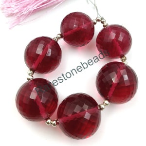 May include: A strand of six faceted red gemstone beads with silver spacers. The beads are round and have a polished finish.