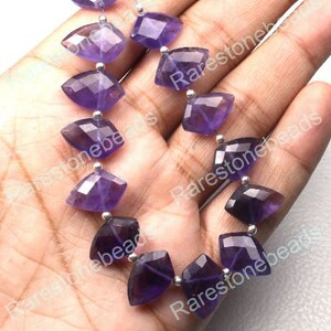 May include: A strand of purple amethyst gemstone beads, each bead is faceted and shaped like a kite. The beads are strung on a silver wire.