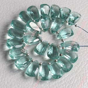 May include: A strand of light blue faceted gemstone beads. The beads are teardrop shaped and strung on silver wire.