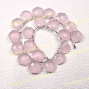 May include: A strand of faceted, light pink gemstone beads. The beads are hexagonal in shape and strung together with silver-colored wire. The beads are arranged in a circular pattern.