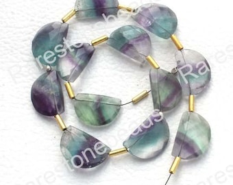 May include: A strand of green, purple, and blue gemstone beads with gold spacers. The beads are half-moon shaped and have a faceted finish.