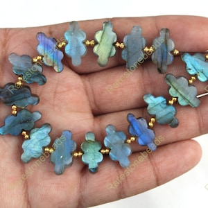 May include: A strand of blue and green labradorite gemstone beads in a flower shape, separated by gold spacer beads.