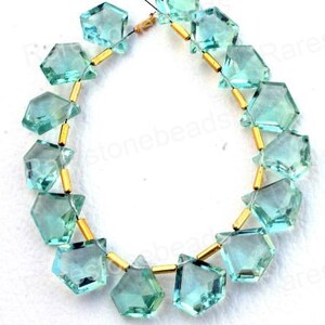 Puede incluir: Una hebra de cuentas de piedras preciosas facetadas de color azul claro con separadores dorados. Las cuentas tienen forma de diamante con esquinas redondeadas. La hebra est&aacute; enhebrada en un hilo transparente.