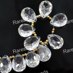 May include: A strand of clear quartz teardrop beads strung on gold wire. The beads are faceted and have a high shine.