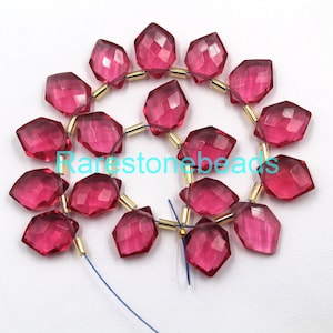May include: A strand of pink faceted gemstone beads with gold spacers. The beads are strung on a blue thread.