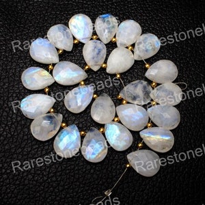 May include: A strand of white moonstone teardrop beads with a rainbow iridescent sheen. The beads are strung on a wire with gold-coloured spacers.