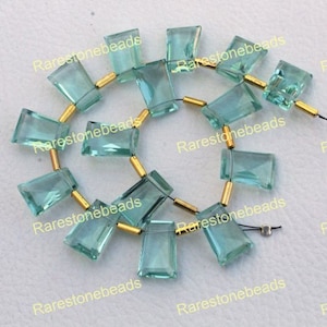 Puede incluir: Una hebra de cuentas de piedra preciosa facetada azul claro con separadores dorados. Las cuentas son rectangulares y tienen una forma ligeramente irregular. Las cuentas están enhebradas en un cordón elástico transparente.