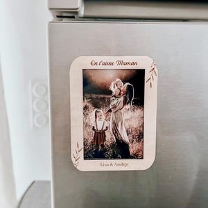 Op de afbeelding: Een houten koelkastmagneet met een familiefoto. De magneet heeft de tekst "On t'aime Maman" en de namen "Lisa & Ambre". De foto toont een vrouw met twee kinderen. De magneet is rechthoekig met afgeronde hoeken.