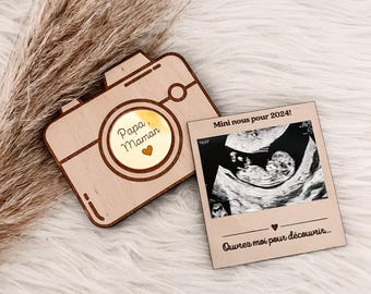 May include: A wooden camera-shaped announcement card with a small ultrasound image and the text "Mini nous pour 2024!" and "Ouvrez moi pour découvrir..."