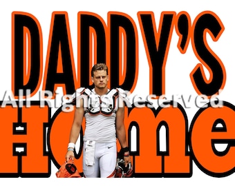 May include: Orange and black graphic with the text "Daddy's Home" in large, bold letters. A young man wearing a white football jersey and black pants is standing in front of the text.