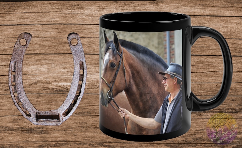 May include: A black ceramic coffee mug with a photo of a brown horse and a person wearing a hat and sunglasses. The mug has a white handle.