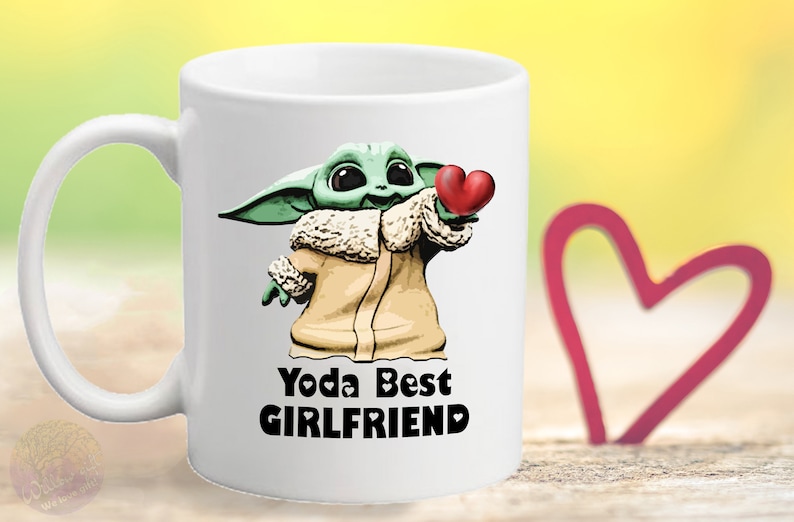 Puede incluir: Taza de cer&aacute;mica blanca con un personaje de dibujos animados verde que sostiene un coraz&oacute;n rojo. El texto "Yoda Best Girlfriend" est&aacute; impreso en la taza.