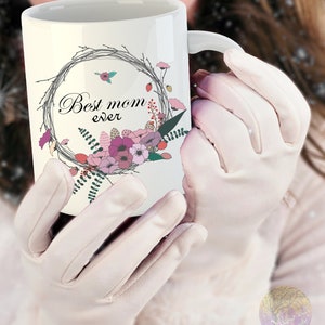 May include: White ceramic mug with a floral wreath design and the text "Best mom ever".
