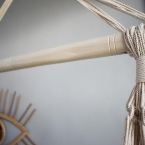 Puede incluir: Primer plano de una varilla de madera natural con cuerda de algod&oacute;n blanco atada alrededor. La cuerda est&aacute; anudada y forma una franja en el extremo.