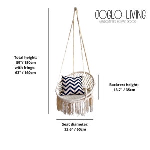 May include: White macrame hanging chair with fringe, a black and white chevron patterned pillow, and a white rope suspension system. The chair is 63 inches tall with fringe and has a 23.6 inch diameter seat. JOGLO LIVING HANDCRAFTED HOME DECOR is printed on the image.