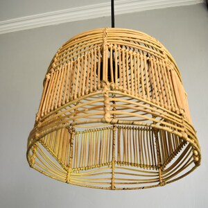 May include: A woven rattan pendant light fixture with a natural beige color. The light fixture is round and has a geometric pattern.