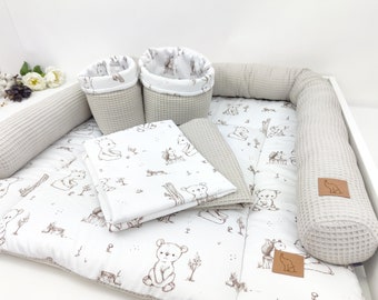 May include: A baby nursery set with a white and brown patterned mattress, two beige waffle weave storage baskets, and two beige waffle weave bumper pads.