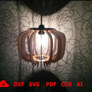 May include: A wooden pendant light fixture with a geometric design. The light fixture is made of multiple layers of wood that are cut into a circular shape. The light fixture is hanging from a ceiling and is illuminated by a light bulb.