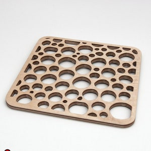 Puede incluir: Un recorte de madera con un patrón de círculos concéntricos. El recorte es de color marrón claro y tiene una superficie lisa.