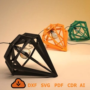 Puede incluir: Tres lámparas colgantes en forma de diamante, una negra, una naranja y una verde. Cada lámpara tiene un diseño geométrico y una bombilla en su interior.