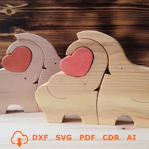 May include: Two wooden elephant figures with hearts on their backs. The elephants are facing each other and are made of light brown wood. The hearts are a light pink colour.
