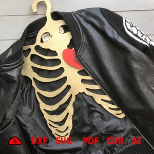 May include: A wooden skeleton-shaped hanger with a red heart cutout. The hanger is hanging on a black leather jacket with a white and black design on the sleeve. The text "DXF SVG PDF CDR AI" is visible at the bottom of the image.