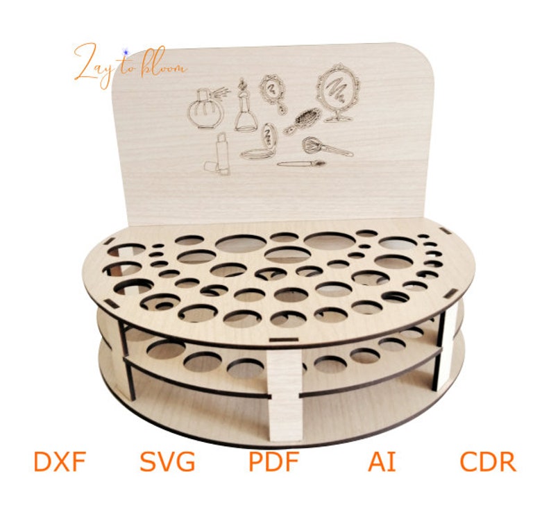 Pu&ograve; includere: Un organizzatore di trucco in legno con una base circolare e due livelli di fori rotondi per riporre i tubetti di rossetto. L'organizzatore ha un pannello posteriore con un design decorativo di articoli da trucco, tra cui un flacone di profumo, un rossetto e uno specchio. Il testo "Zay to bloom" &egrave; stampato sul pannello posteriore.