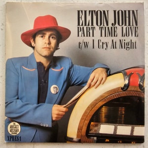 Könnte beinhalten: Ein Vintage-Schallplattencover mit Elton John, der einen roten Hut und einen blauen Anzug trägt. Der Albumtitel lautet "Part Time Love" mit der B-Seite "I Cry At Night".